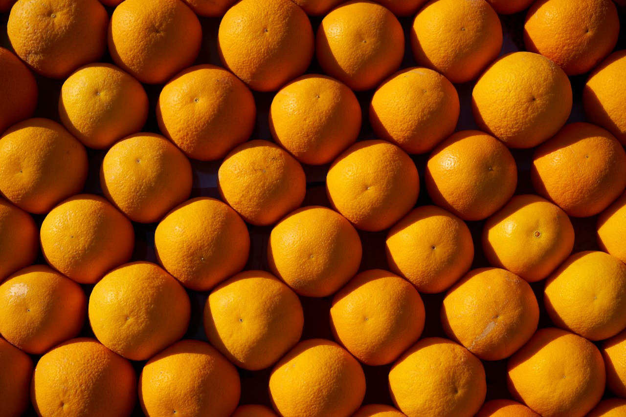 Top view of a neatly arranged pile of fresh oranges, showcasing vibrant color and texture.